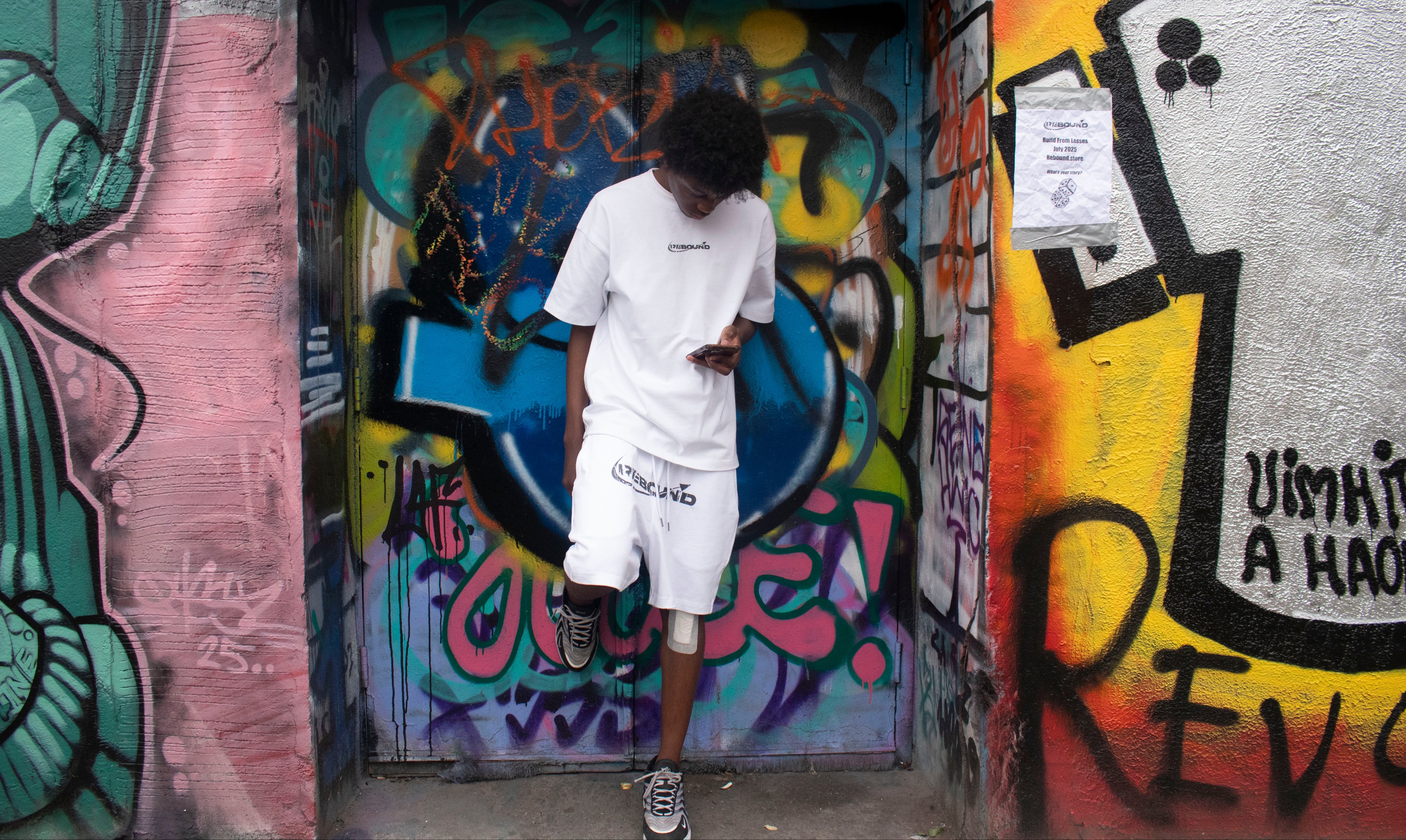 Person standing in front of a colorful graffiti-covered wall