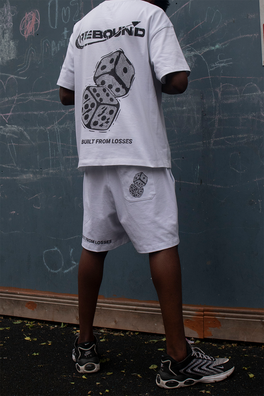 Rebound streetwear model in clean white tee standing confidently in front of blue urban wall