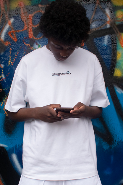 Model wearing Rebound white logo t-shirt, looking down, shot against colorful graffiti wall